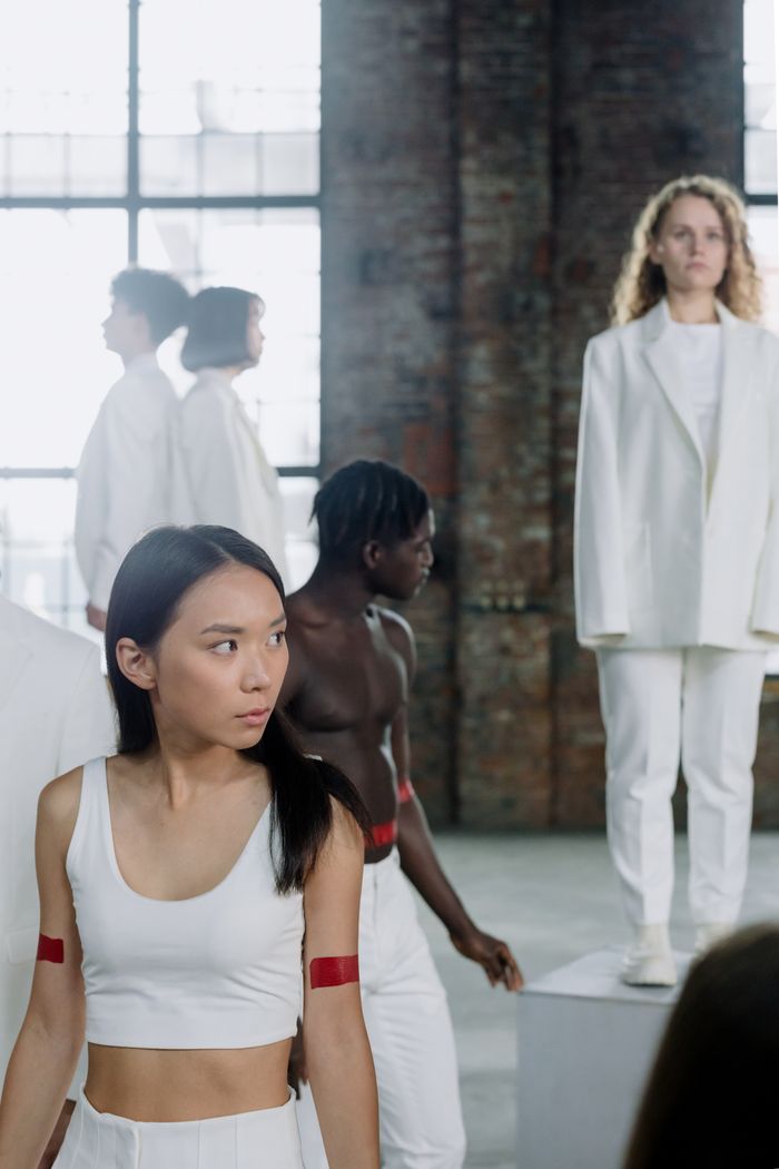 Group of diverse individuals in white attire showcasing modern fashion in an industrial space.