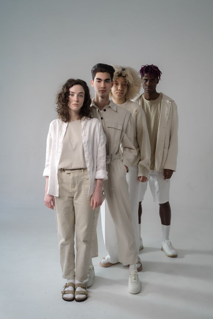 A stylish group of diverse models in neutral tones, set in a studio.